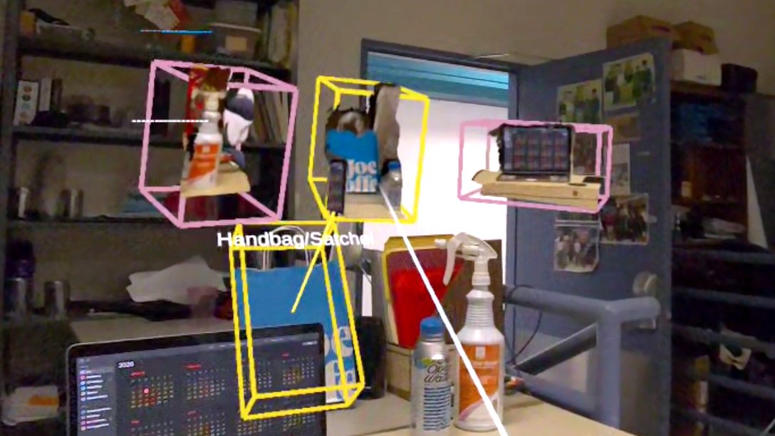 Headset passthrough view of a lab desk. Proxies of a spray bottle, a bag and a laptop float in wireframe boxes. A controller ray points at the bag proxy, whose box turns yellow, and a yellow line runs from it to the real bag, which is outlined by a yellow box labeled Handbag/Satchel.